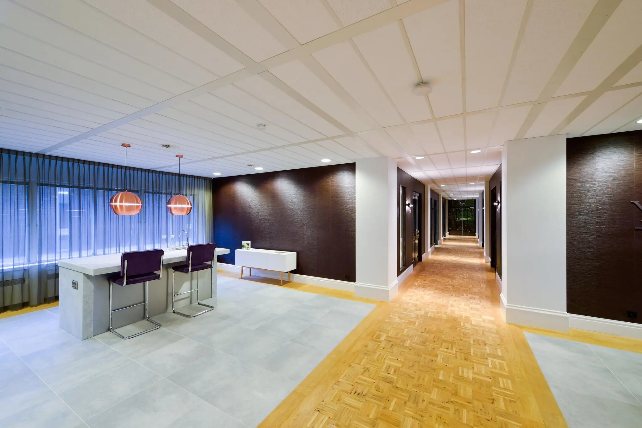 Moderne, strak ingerichte hal met zithoek en marmeren kookeiland in een gebouw aan de Floris Grijpstraat.